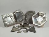 several pieces of silver metal are arranged on a white surface