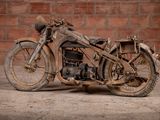 a old motorcycle that is sitting in front of a brick wall