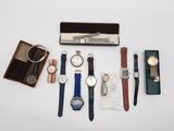 Plusieurs montres et autres objets sont disposés sur une surface blanche