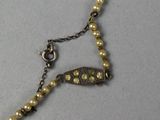rosary chain with pearls and gold beads on a gray surface