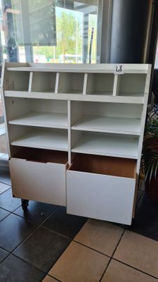a close up of a white book shelf with two drawers
