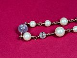 a close up of a necklace with pearls on a pink background