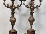 pair of antique bronze candelabs on pedestals on a white background
