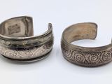 two silver bracelets with engraved designs on them on a white surface