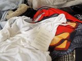 a pile of clothes and a teddy bear on a bed