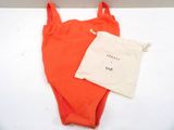 an orange one piece swimsuit with a draws bag on a white surface