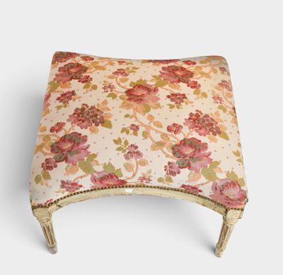 an upholstered foot stool with a floral pattern and gold trim