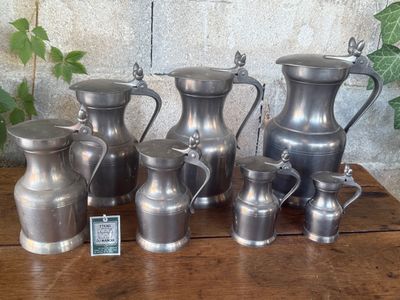 a lot of silver vases sitting on a wooden table