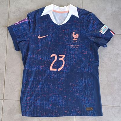 Le maillot est bleu et porte le numéro 23 en rose.