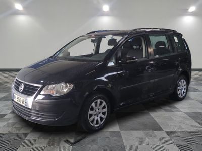 La Volkswagen Touran noire est garée sur un sol en carrelage à damier.
