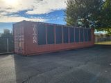 a red shipping container sitting in the middle of a parking lot