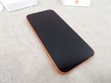 an image of a black and orange phone laying on a bed