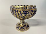 a blue and gold bowl sitting on a white surface