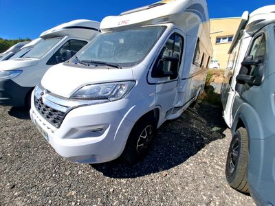 trois camping-cars blancs garés les uns à côté des autres sur un parking