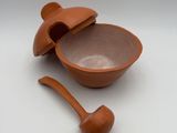 a brown bowl with a spoon in it on a white surface
