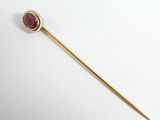 a close up of a gold stick with a red stone on it