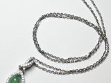 chaîne en argent avec un pendentif vert en forme de larme sur fond blanc