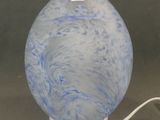 une boule en verre bleue et blanche posée sur un socle blanc