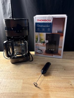 une cafetière noire et une boîte posées sur une table en bois