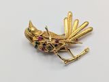 a close up of a bird brooch on a white surface