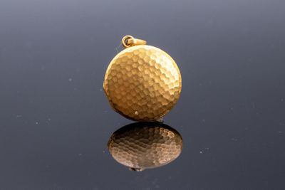 une image représentant une boule plaquée or posée sur une surface réfléchissante