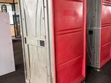 Plusieurs toilettes portables sont alignées dans une zone d'entrepôt