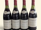 four bottles of wine are lined up on a white surface