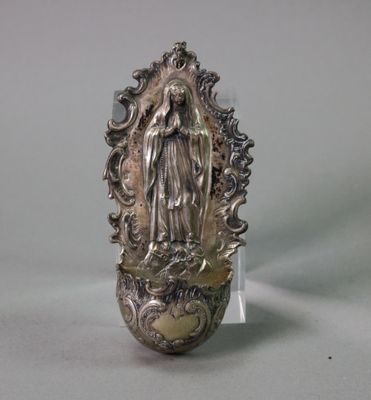 a silver statue of the virgin of guadalupe on a glass stand