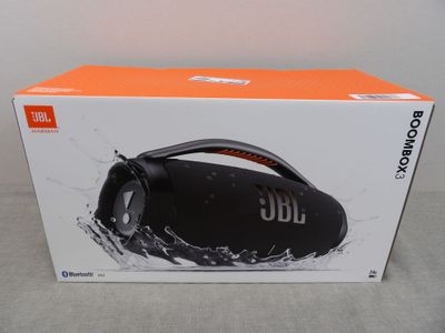 La boîte de la Boombox JBL est ouverte sur la table.
