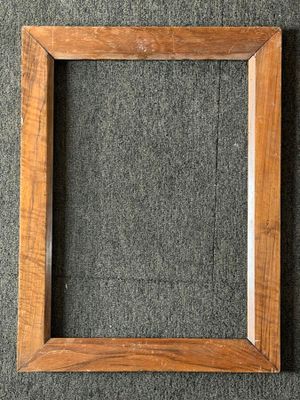 an empty wooden frame on a gray carpet