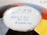 a colorful vase with writing on it with a beach ball in the background