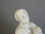 a white statue of a man with his hands crossed