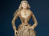 an antique doll of a woman in a dress made of shells