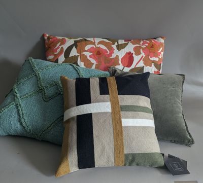 three pillows with different colors and patterns on them on a gray background