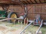 un tracteur garé dans une grange, à côté d'une clôture en bois