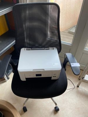 a white printer sitting on top of a black chair