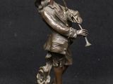 bronze figurine of a man playing a trumpet on a black background