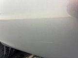 the side of a white car with a dent on it