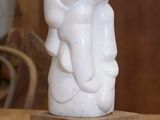 une statue blanche représentant un éléphant, posée sur un socle en bois