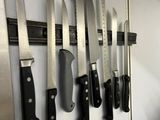 a lot of knives hanging on the wall in the kitchen
