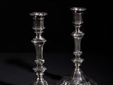 pair of silver candlesticks on a black surface with a black background