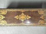 an old wooden box with a gold and brown design on it