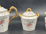 three pieces of porcelain teapots with gold handles and flowers