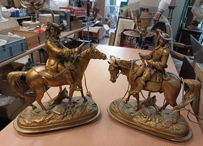two bronze statues of men riding horses on a table