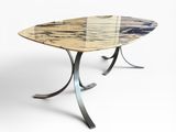 une table à manger ovale en marbre, avec des pieds en métal et un plateau en verre