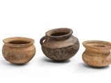 trois pots en argile sont posés les uns à côté des autres sur une surface blanche