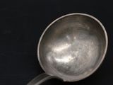 a silver spoon with a spoon handle on a black surface