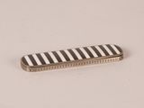 a close up of a black and white striped comb on a white surface