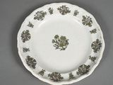 a white plate with green flowers on it on a table