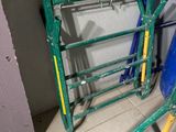 a pile of green and yellow ladders next to a blue trash can
